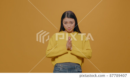 Asian woman doing praying gesture with hands and begging 87789407