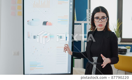 Businesswoman pointing at television with data charts Businesswoman pointing at television with data charts 87790220