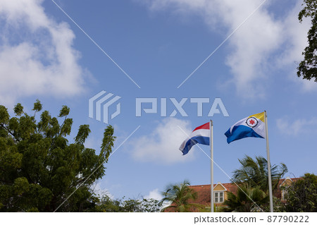 Flag of Bonaire and Netherlands flying in the wind on the blue sky background. Flag of Bonaire and Netherlands flying in the wind on the blue sky background. 87790222