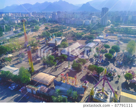 Panoramic view of the city through the glass. Riding tourists on a Ferris wheel. around greenery, attractions and nature 87791111