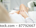 Skinny woman with beautiful legs with well-groomed leather lies on a white beauty table 87792667