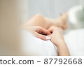 Skinny woman with beautiful legs with well-groomed leather and crossed arms lies on a white beauty table 87792668