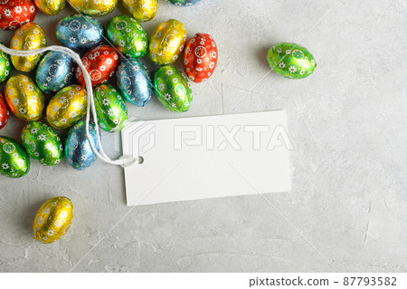 White rectangular Easter tag mockup with Happy Easter chocolate easter eggs on grey stone background 87793582