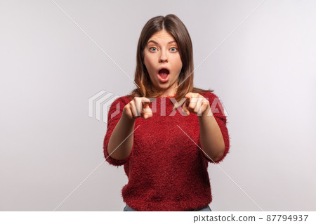 Wow, hey you. Portrait of amazed shocked brunette woman in shaggy sweater pointing finger to camera, looking with surprise, noticing and making choice. indoor studio shot isolated on gray background Wow, hey you. Portrait of amazed shocked brunette woman in shaggy sweater pointing finger to camera, looking with surprise, noticing and making choice. indoor studio shot isolated on gray background 87794937