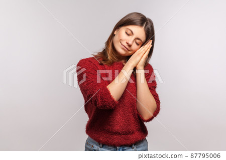 Bedtime. Portrait of girl in shaggy sweater sleeping laying down on her palms and smiling pleased, having comfortable nap and resting, dozing off. indoor studio shot isolated on gray background 87795006