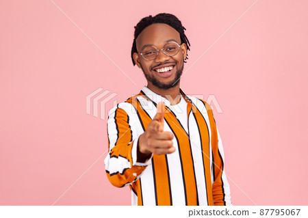 Positive smiling afro-american man with dreadlocks in striped shirt choosing you, pointing finger at camera, happy satisfied with your achievements. Indoor studio shot isolated on pink background 87795067