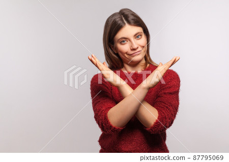 Definitely no, prohibited access. Portrait of girl in shaggy sweater crossing hands, showing x sign, stop gesture, warning of end finish, forbidden way. indoor studio shot isolated on gray background Definitely no, prohibited access. Portrait of girl in shaggy sweater crossing hands, showing x sign, stop gesture, warning of end finish, forbidden way. indoor studio shot isolated on gray background 87795069