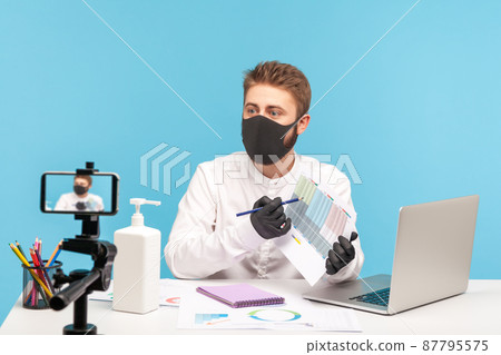 Masked and gloved man employee showing document with schedule table to cellphone camera, having online conference at home office workplace, distance learning webinar. indoor studio shot isolated Masked and gloved man employee showing document with schedule table to cellphone camera, having online conference at home office workplace, distance learning webinar. indoor studio shot isolated 87795575