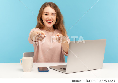 Hey, you are awesome. Positive businesswoman in casual clothes pointing to camera, making choice and gesturing We need you, sitting at her workplace home office. indoor studio shot, blue background 87795825