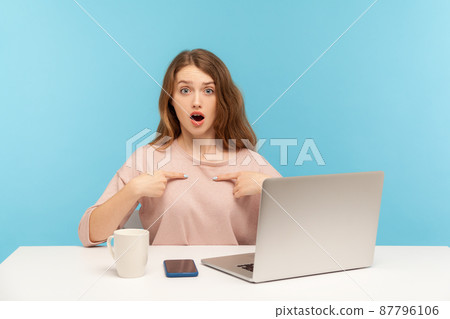 This is me. Amazed woman employee pointing herself and looking at camera with surprised expression, shocked by her job achievement, sitting at workplace with laptop. indoor studio shot, isolated This is me. Amazed woman employee pointing herself and looking at camera with surprised expression, shocked by her job achievement, sitting at workplace with laptop. indoor studio shot, isolated 87796106