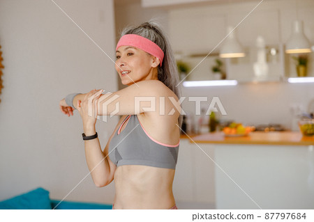 Sporty woman stretching arms during home workout 87797684