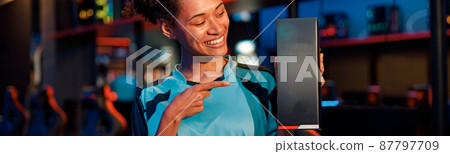 Happy woman gamer stands in room of gaming club Happy woman gamer stands in room of gaming club 87797709
