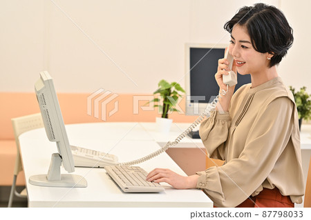 A woman calling in front of a disk computer in the office A woman calling in front of a disk computer in the office 87798033