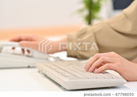 一個女人在敲鍵盤時伸手去拿聽筒 87798050