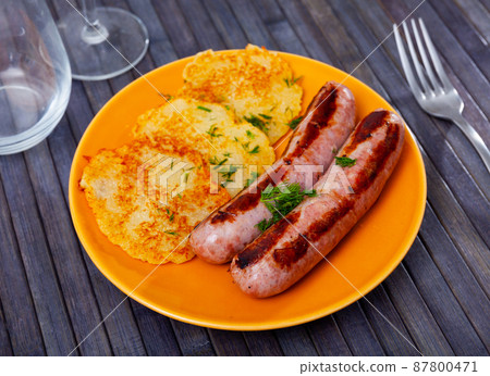 Fried potato pancakes with grilled pork sausages 87800471