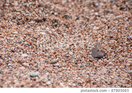 Small sea pebbles with stones with a reddish tint 87803083