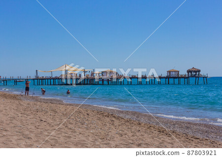 Pier and beach on a clear day with blue sea 87803921