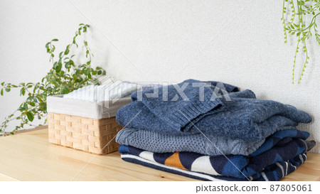 Folded winter clothes and towels in a basket. Image of changing clothes and laundry. 87805061