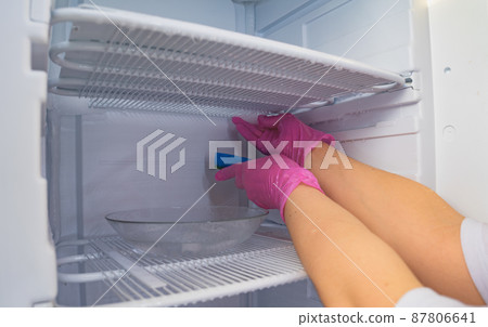 A cleaning lady washes the freezer. Cleaning the refrigerator. Selective focus. A cleaning lady washes the freezer. Cleaning the refrigerator. Selective focus. 87806641