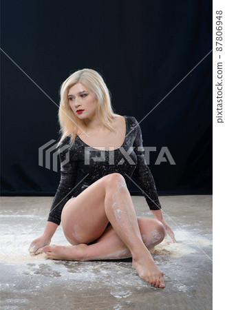 Plump blonde girl wearing a black gymnastic bodysuit covered with clouds of the flying white powder 87806948