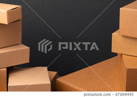 Stack of cardboard boxes against black background Stack of cardboard boxes against black background 87809495