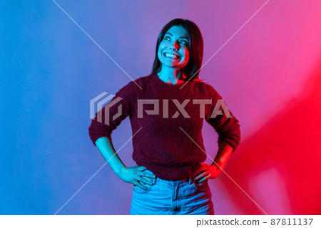 Happy emotions. Neon light portrait of joyful delighted woman in pullover looking up with wide toothy smile, cheerful grinning, laughing after hearing funny joke, anecdote. indoor studio shot isolated Happy emotions. Neon light portrait of joyful delighted woman in pullover looking up with wide toothy smile, cheerful grinning, laughing after hearing funny joke, anecdote. indoor studio shot isolated 87811137
