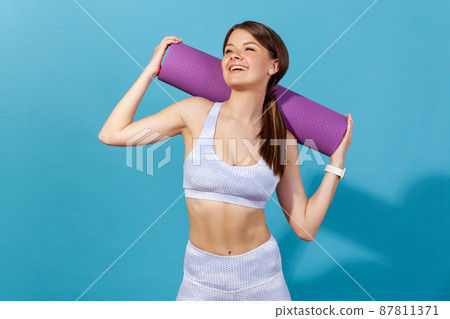 Studio Shot Of Slim Sporty Woman Holding Yoga Mat Before Or After