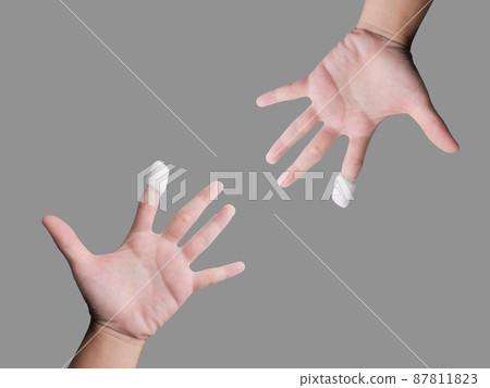 Two hands pointing a wounded finger was treated with gauze attached To clean and prevent infection of the wound. Isolated image with gray background. Put clipping paths, copy space ready to use. Two hands pointing a wounded finger was treated with gauze attached To clean and prevent infection of the wound. Isolated image with gray background. Put clipping paths, copy space ready to use. 87811823