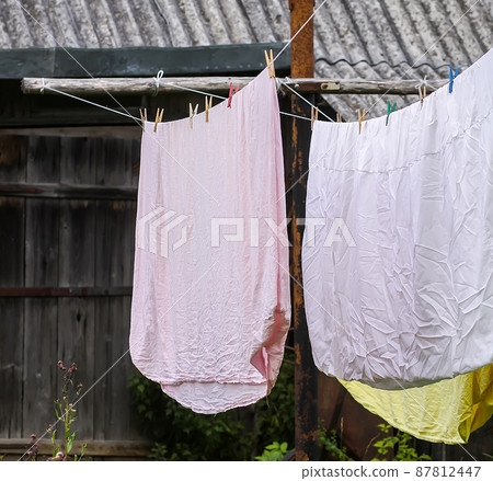 Freshly washed bed linen hanging on the rope outdoors. 87812447