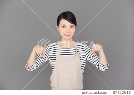 Female in apron pointing with finger 87812618