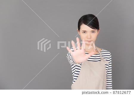 A woman in an apron who puts out her hand and stops A woman in an apron who puts out her hand and stops 87812677