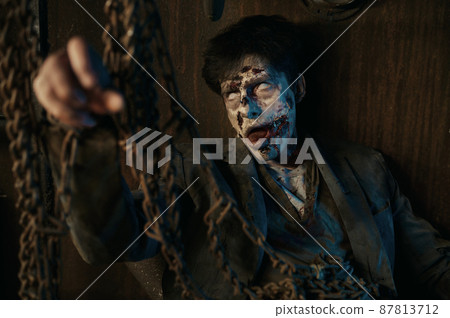 Chained zombie in basement of abandoned house 87813712