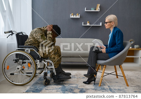 Soldier in camouflage holding head in hands 87813764