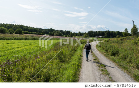 Woman walking on a path at the Swedish countryside Woman walking on a path at the Swedish countryside 87814519