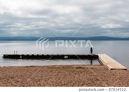 Woman standing on a rectanguar shaped pier at the Ljusnan river Woman standing on a rectanguar shaped pier at the Ljusnan river 87814522