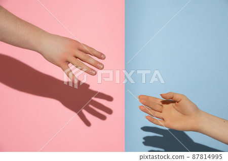 Male and female hands isolated on pink and blue colors background. Concept of relationships, friendships, peace and support Male and female hands isolated on pink and blue colors background. Concept of relationships, friendships, peace and support 87814995