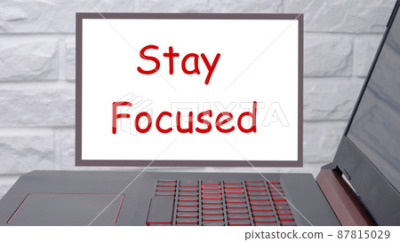STAY FOCUSED a phrase written on a magnetic board next to a laptop with a glowing keyboard 87815029