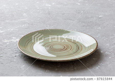 Perspective view of empty green plate on cement background. Empty space for your design 87815844
