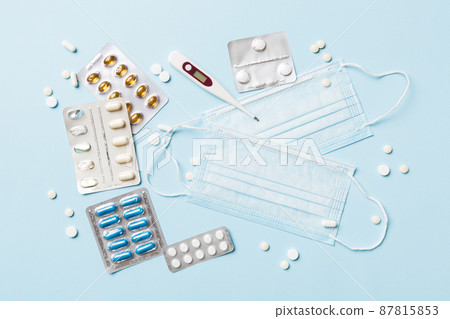 Protective face masks or surgical masks, medicine pills and thermometer on table background. Coronavirus disease. Corona virus concept. Space for text Protective face masks or surgical masks, medicine pills and thermometer on table background. Coronavirus disease. Corona virus concept. Space for text 87815853