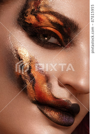 Portrait of a beautiful woman with creative fire art make-up on her face. 87815955