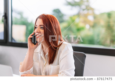 Young woman using mobile phone while working at home 87817475