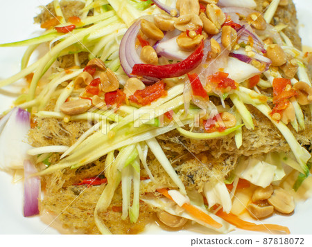 Fried catfish salad topped with lime sauce, mango meat and fresh chili. 87818072