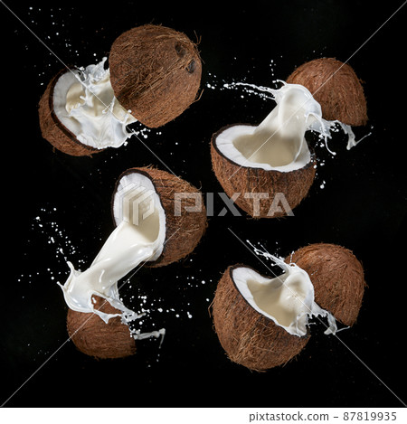Cracked Coconuts milk water splash flying in the air. Cracked Coconuts milk water splash flying in the air. 87819935