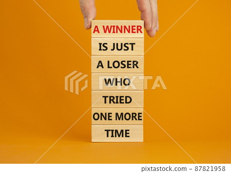 Winner or loser symbol. Wooden blocks with words A winner is just a loser who tried one more time. Beautiful orange background, copy space. Businessman hand. Business, winner or loser concept. 87821958