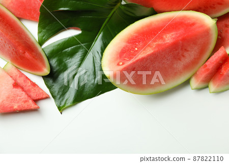 Juicy watermelon slices and palm leaf on white background 87822110