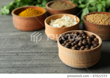 Different spices in wooden bowls on gray textured background 87822555
