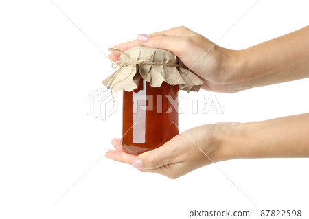 Female hands hold jar of peach jam, isolated on white background Female hands hold jar of peach jam, isolated on white background 87822598