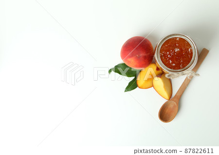 Jar of peach jam, ingredients and spoon on white background 87822611