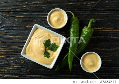 Bowls with cheese sauce and pepper on wooden table 87823211