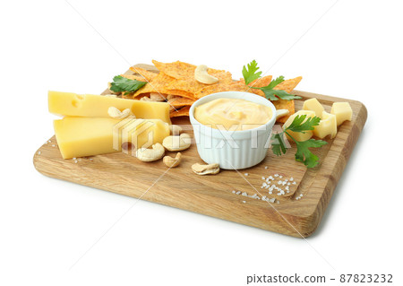 Board with cheese sauce and snacks isolated on white background 87823232